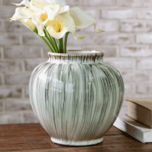 A ceramic vase with flowers on a wooden table.